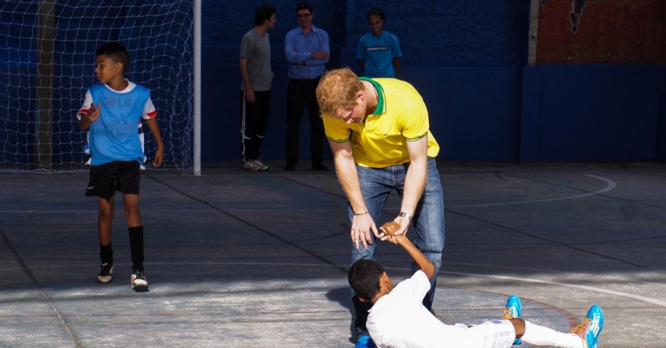 25.jun.2014 - Com a camisa do Brasil, Príncipe Harry joga futebol com crianças de projeto social em Diadema