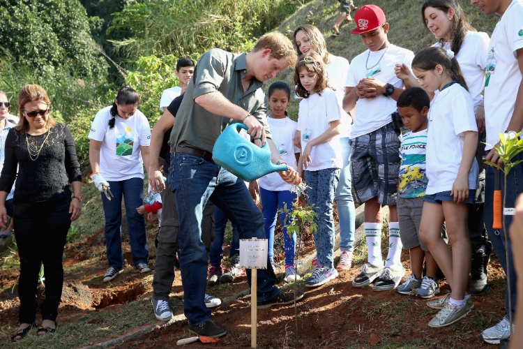 25.jun.2014 - Na frente de várias crianças, Príncipe Harry rega muda de árvore que plantou durante visita à Comunidade Cota 200, em Cubatão, no litoral de São Paulo