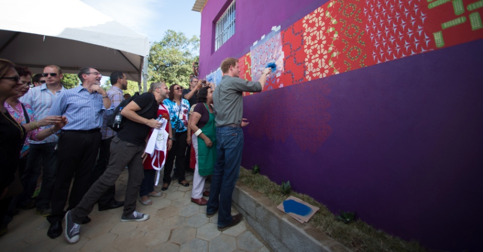 25.jun.2014 - Príncipe Harry pinta muro de uma casa durante visita à Comunidade Cota 200, em Cubatão, no litoral de São Paulo