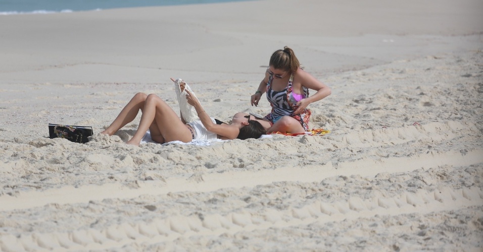 26.jun.2014 - Isis Valverde conversa com amiga enquanto toma sol na praia da Reserva, no Rio de Janeiro