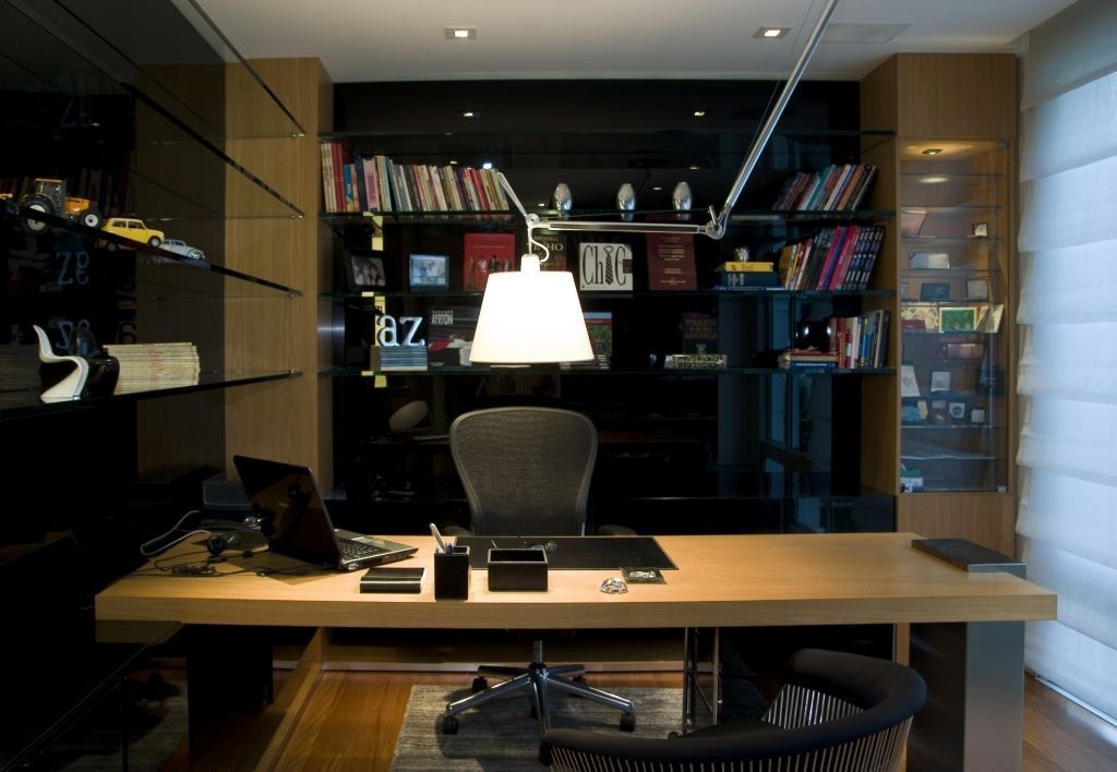 A arquiteta Ieda Koman destacou as colunas de madeira e o tampo da escrivaninha neste escritório residencial, optando pelo preto como fundo para as estantes amplas. As prateleiras, porém, são feitas de vidro dando leveza ao ambiente - Divulgação