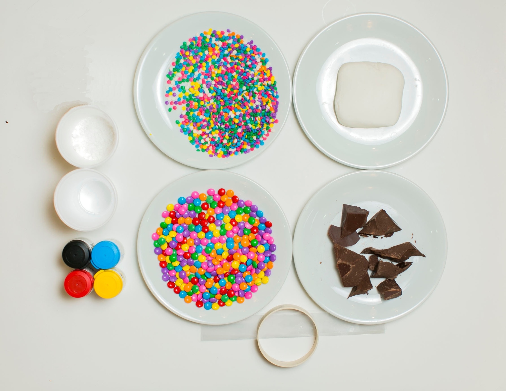 Confira os materiais necessários para fazer o pirulito de chocolate: água; açúcar de confeiteiro; tinta em gel comestível nas cores desejadas; confeito de chocolate em cores e tamanhos diferentes; pasta americana; chocolate ao leite fracionado; vazador redondo; plástico para o vazador; palitos; colher; recipiente que possa ir ao micro-ondas ou para o banho-maria e luva - Leonardo Soares/UOL