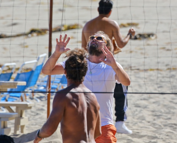 6.jul.2014 - De óculos escuros e cabelos presos, Leonardo DiCaprio joga vôlei na praia em Malibu, na Califórnia. O ator estava acompanhada da namorada, Toni Garn