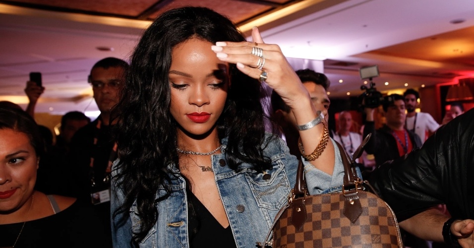11.jul.2014 - Rihanna deixa o hotel em Copacabana cercada por seguranças. A cantora coloca a mão no rosto para evitar os flashes