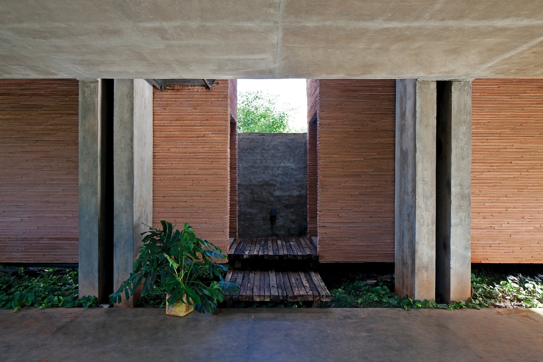 Dois pilares de seção 0,27 m x 0,8 m compõem o eixo de sustentação da House in the Air. Ao fundo, os dois blocos - um de serviços, outro para circulação vertical (escadarias) - de 11 m² cada, servem como contrapeso ao volume principal, que fica suspenso a 2,80 m de altura do solo. Os contrapesos não estão sobre o solo, eles também "flutuam" distantes 0,8 m do chão. Tudo é estruturado em concreto armado reforçado. A casa tem design da TDA Arquitetura e fica em Luque, Paraguai - Leonardo Finotti/ UOL