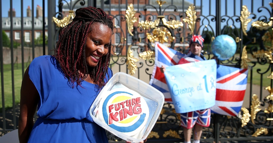Mulher mostra bolo com os dizeres "futuro rei" no aniversário do Príncipe George em frente ao Palácio de Kensington, em Londres