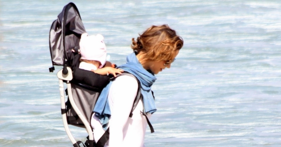 23.jul.2014 - Com a filha Minna nas costas, Guilhermina Guinle passeia na praia de Ipanema, na zona sul do Rio