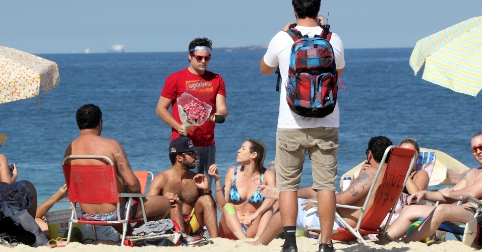 1.ago.2014 - Repórter Vesgo do "Pânico" aborda Luana Piovani com um buquê de flores na praia do Leblon