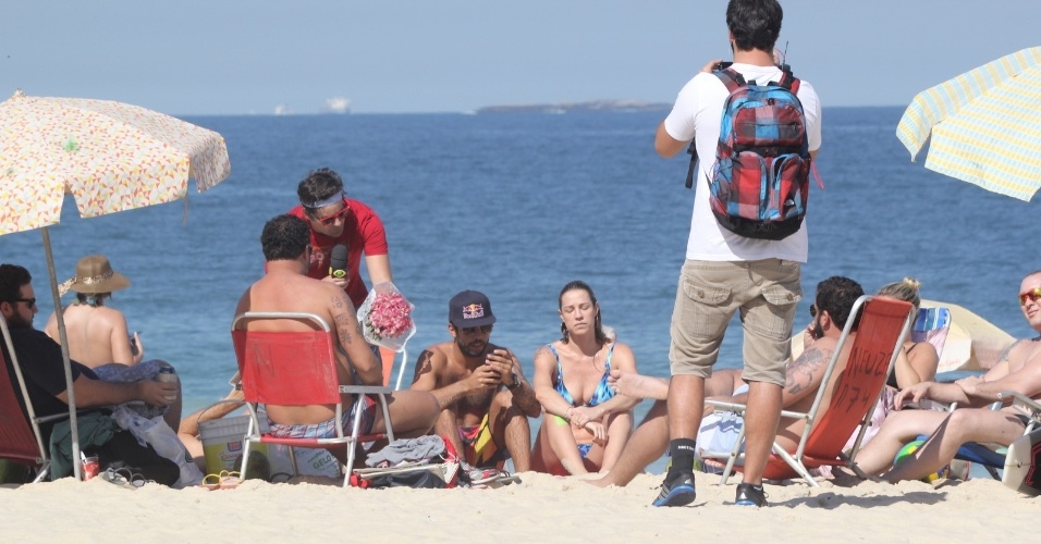1.ago.2014 - Repórter Vesgo do "Pânico" aborda Luana Piovani com um buquê de flores na praia do Leblon