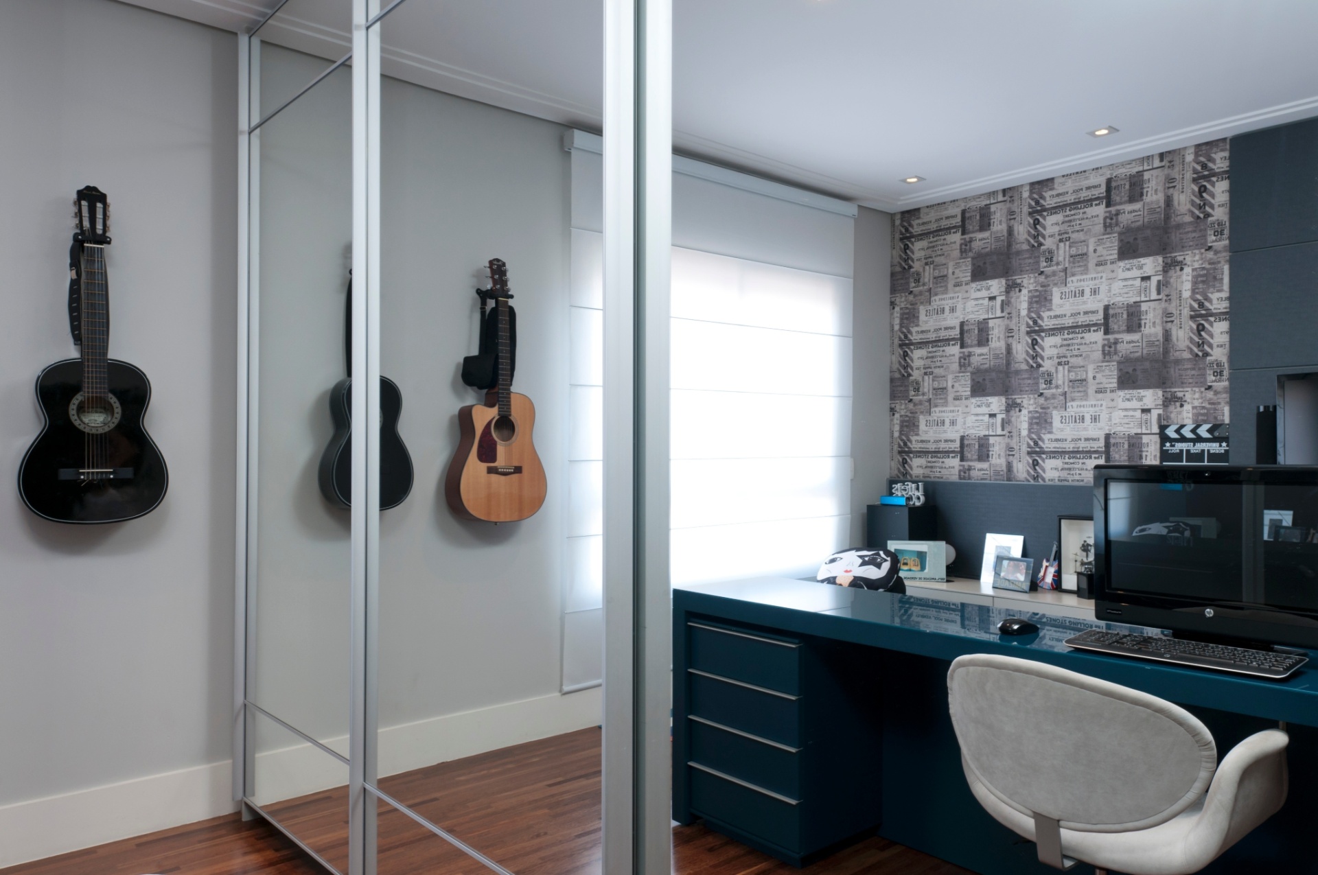 Deste ângulo do quarto idealizado pela arquiteta Ana Bartira Brancante (www.anabartira.com.br), é possível ver como a escrivaninha divide o espaço em dois cantos distintos: o de trabalho e o de descanso. As portas de correr espelhadas do armário não só ganham espaço físico como dão a sensação visual de maior amplitude. O projeto reservou área na parede para os violões - Raul Fonseca/Divulgação