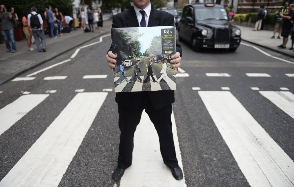 8.ago.2014 - Fã carrega o álbum "Abbey Road", com a icônica imagem dos integrantes dos Beatles atravessando a rua - Andy Rain/EFE