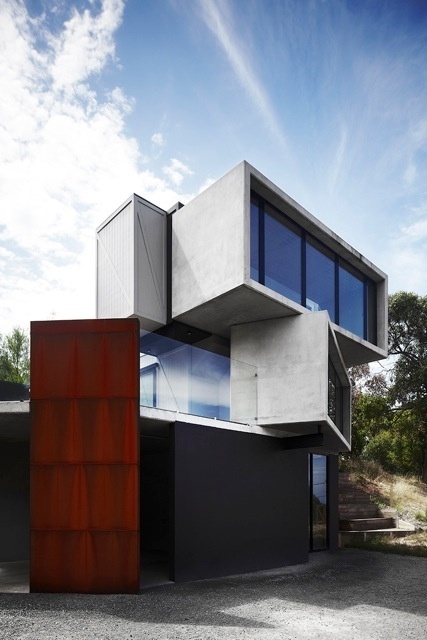Os arquitetos do escritório Whiting criaram a fachada da "Pod House" usando chapa de aço cortén "patinada" naturalmente pela ferrugem. Seu avermelhado rústico quebra o cinza das caixas de concreto empilhadas e cria um volume vertical que vai do piso térreo até a altura máxima do guarda-corpo do terraço, no primeiro andar. A arquitetura, ao criar uma rotação dos três volumes sobre um eixo, faz com que a casa se volte para um horizonte em 180°. A casa "Pod" fica em Lorne, na costa australiana - Sharyn Cairns/ Divulgação