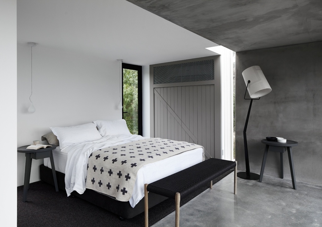 A porta de vidro duplo do dormitório dá acesso ao terraço posterior, privativo para o casal (face norte). Na "Pod House", portas, janelas e caixilhos são em alumínio pintado e tratado com gás argônio, anticorrosivo que aumenta a durabilidade frente à maresia. O guarda roupas é de MDF cinza e acompanha a cor da grelha de alumínio que embute o ar-condicionado. A cama está sobre um carpete e o restante do acabamento acinzentado é feito num cimento queimado espatulado. Em Lorne, Austrália - Sharyn Cairns/ Divulgação