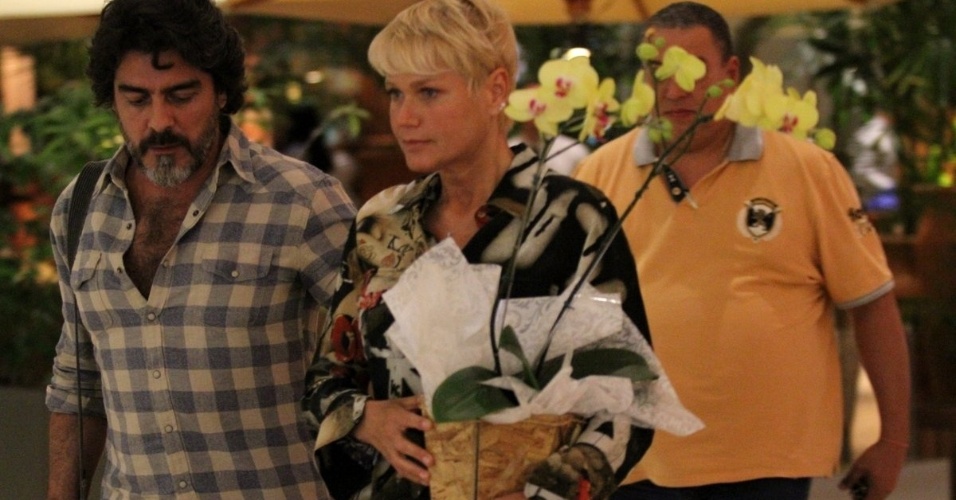 11.set.2014 - Segurando um vaso de orquídeas, Xuxa é vista passeando em shopping com o namorado, Junno