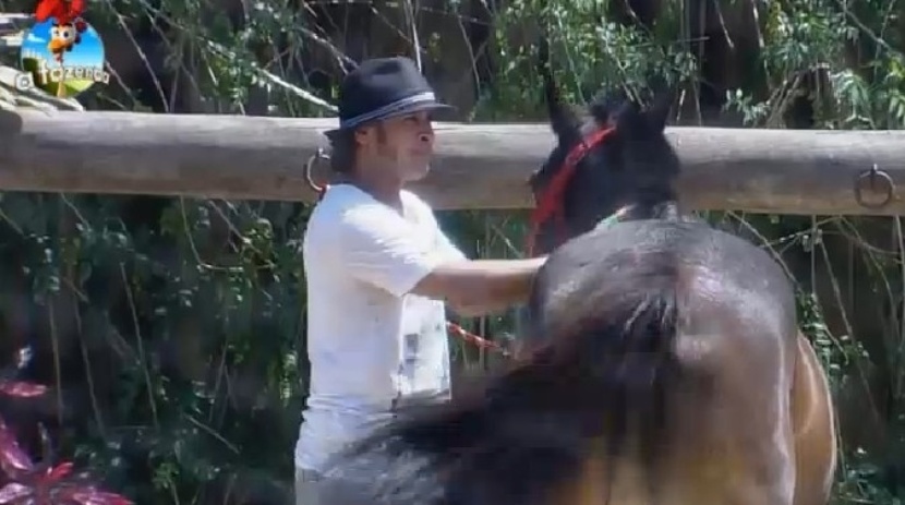 Roy Rossello escova o cavalo enquanto é observado pelo caseiro e outros peões