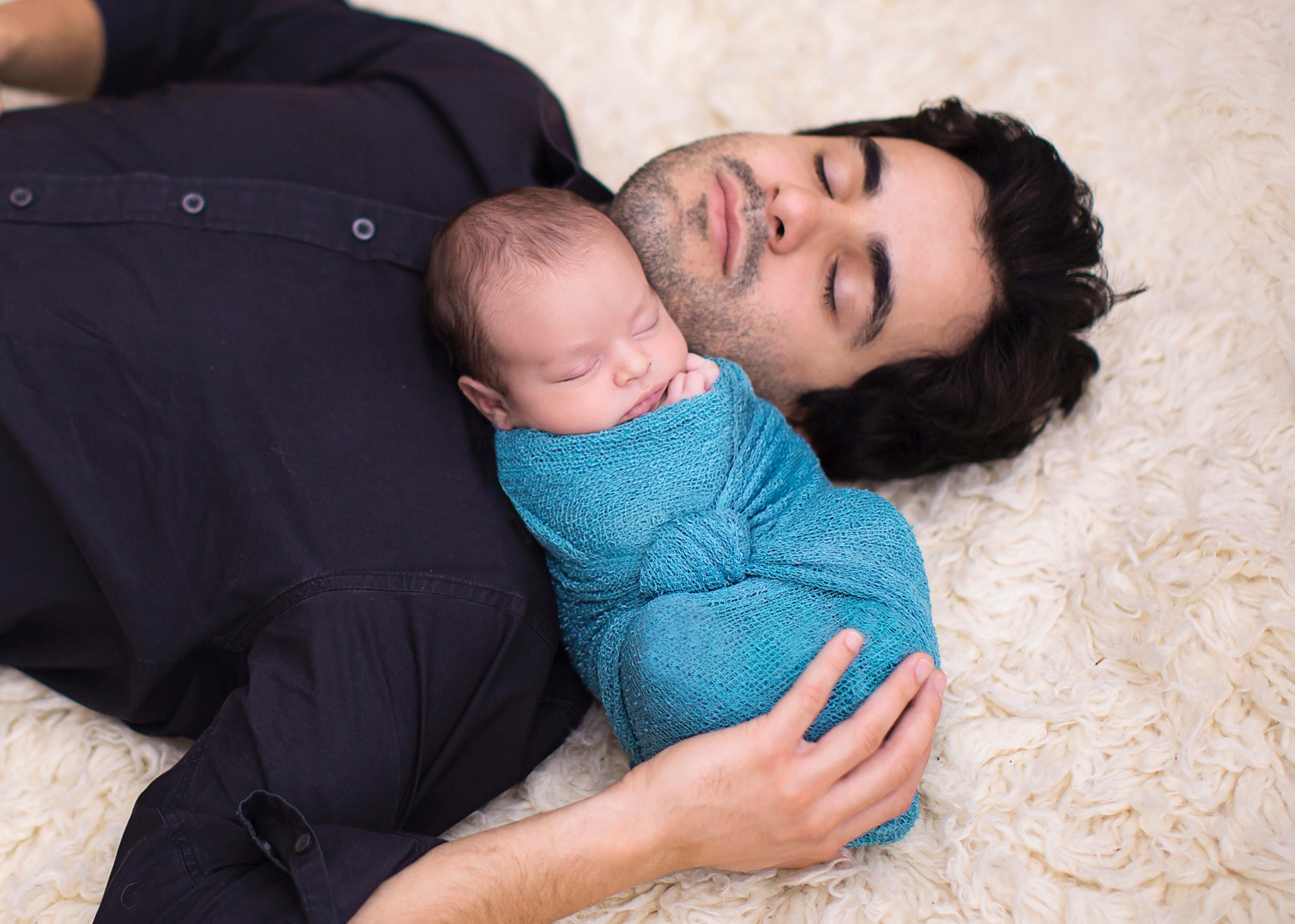 Para que as fotos de pai e filho mostrem naturalidade e fiquem bonitas, fotógrafos investem na simplicidade e em acessórios. Na imagem, a fotógrafa Elieen Parker enrolou Matheus em um pano azul e o apoiou no pai, Fernando - Eileen Parker/Divulgação