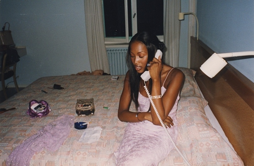 Em um possível quarto de hotel, a modelo Naomi Campbell falando ao telefone