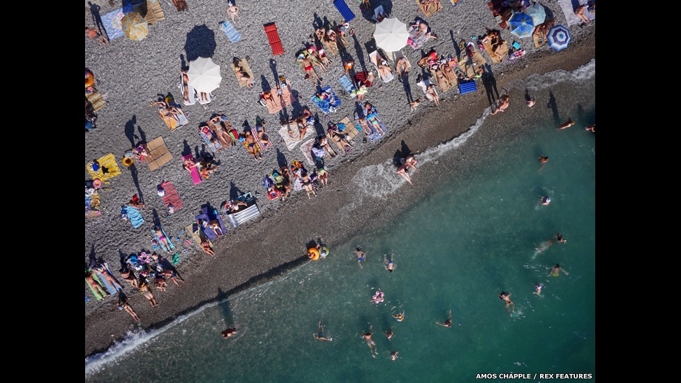 O fotógrafo neo-zelandês Amos Chapple usou uma câmera acoplada a um drone para tirar fotos aéreas de alguns dos mais belos pontos turísticos da Europa. Ao lado, vários turistas se banham em uma praia no Mar Negro, na Abecásia (território autônomo na Geórgia). - Amos Chapple/Rex Features