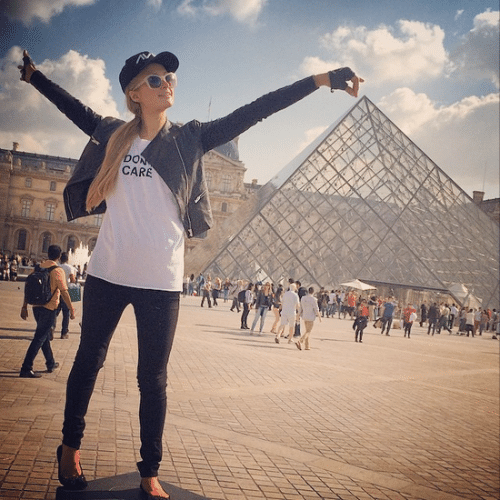 3.out.2014 - Em foto clássica, Paris Hilton tenta, mas erra o alvo ao fingir que segura a ponta da pirâmide de vidro o Museu do Louvre, em Paris, na França