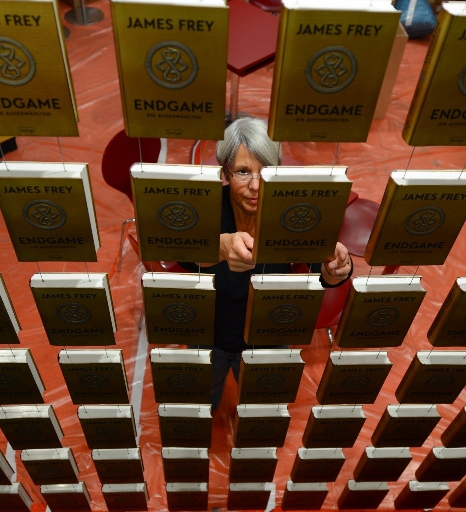 07.out.2014 - Funcionária da Feira do Livro de Frankfurt expõe o livro da série "End Game", de James Frey - AFP