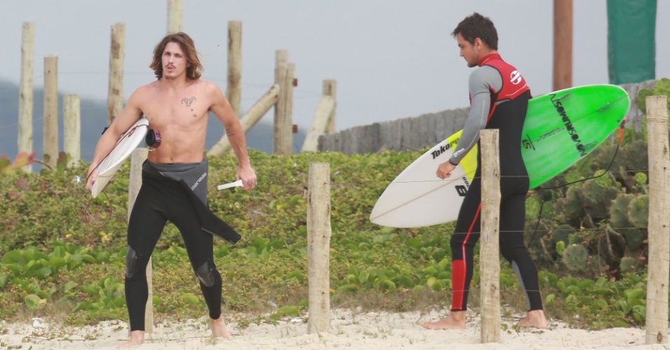 23.out.2014 - Sem camisa e acompanhado de amigo, Rômulo Neto chega à praia da Reserva, no Rio, para surfar