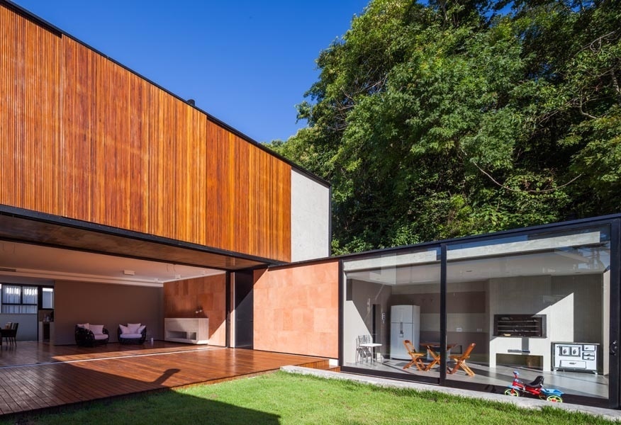 Uma das laterais da NSN House, criada pelo escritório Biselli Katchborian Arquitetos, abriga área de serviço, churrasqueira e sauna voltadas para o jardim. O revestimento em arenito vermelho de parte das volumetria entra em sintonia com a madeira cumaru empregada nos painéis do pavimento superior - Nelson Kon/ UOL