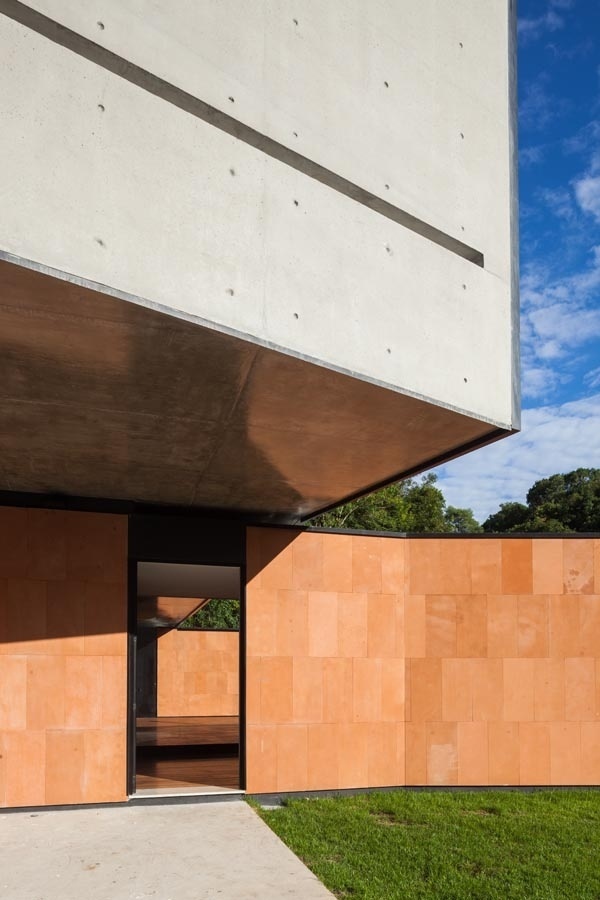 A fachada principal da NSN House, projetada pelo escritório Biselli Katchborian Arquitetos, se destaca pela sobreposição de volumes esculturais e pelo contraste dos revestimentos: concreto aparente na empena cega (com rasgo horizontal) e placas de arenito vermelho paranaense - Nelson Kon/ UOL