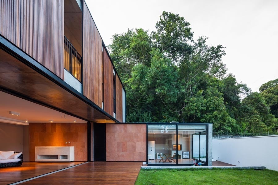 Uma das laterais da NSN House, criada pelo escritório Biselli Katchborian Arquitetos, abriga área de serviço, churrasqueira e sauna voltadas para o jardim. O revestimento em arenito vermelho de parte das volumetria entra em sintonia com a madeira cumaru empregada nos painéis do pavimento superior - Nelson Kon/ UOL