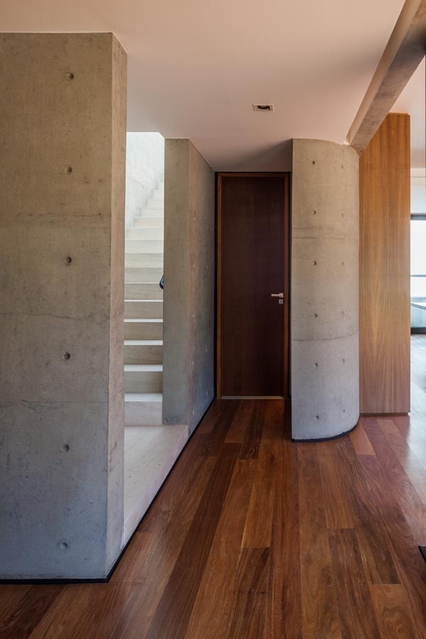 Para delimitar a área do lavabo, uma parede curva de concreto foi erguida. A estrutura também esconde a pia ali instalada. O contraste quente/ frio aparece no mix de materiais utilizados nesta casa curitibana, como o concreto aparente e a madeira cumaru que reveste o piso. A NSN House foi projetada pelo escritório Biselli Katchborian Arquitetos - Nelson Kon/ UOL