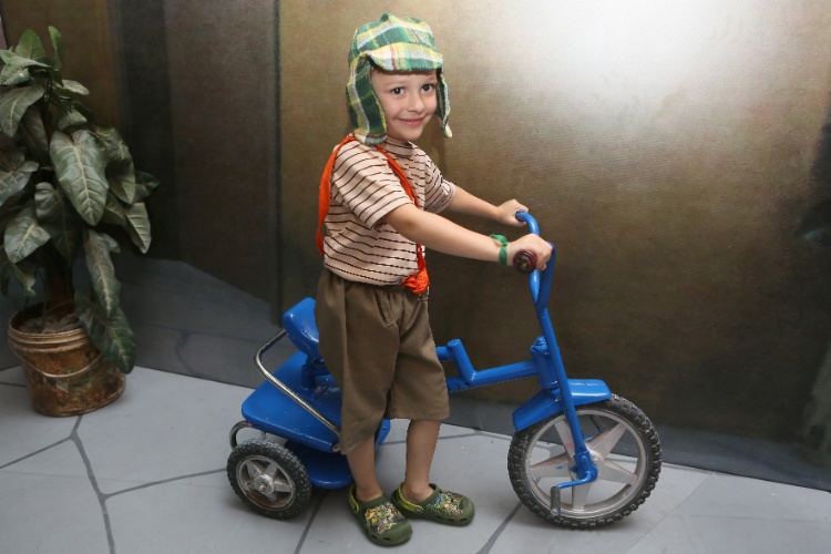30.nov.2014 - O pequeno fã de Chaves, Guilherme Mansano de Jesus, de 4 anos, posa com o velotrol da exposição montada pelo SBT, que reproduz a vila do Chaves e sua turma