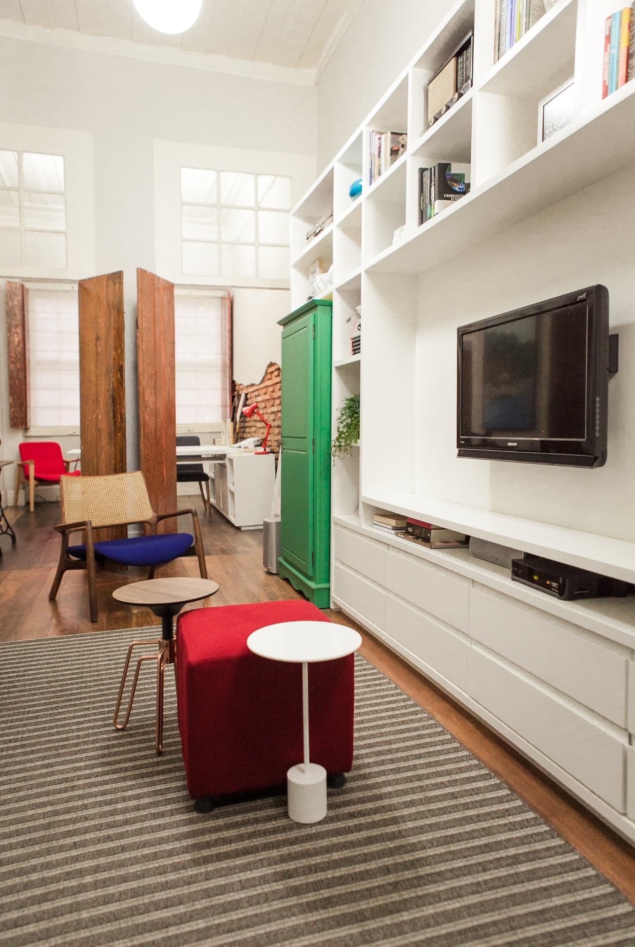 A ambientação do estar com home theater do Sobrado 505, em Florianópolis (SC), aposta em marcenaria reta e branca (Lineabella), além de mobília em tons de cinza - como sofá e tapete - e peças coloridas de antiquário, que passaram por restauro, como é o caso do armário verde (pintura laqueada fosca). Também há elementos assinados pelo designer Jader Almeida, como as mesas de centro e de apoio. Os projetos de reforma e interiores são assinados por Elaine Gerente e Luiza Porto, do Studio UM - Mauri Cherobin/ Divulgação