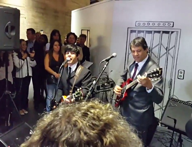 16.dez.2014 - Prefeito de São Paulo Fernando Haddad toca guitarra com a banda Beatles 4ever durante a abertura da exposição "O Mundo de Mafalda" - Reprodução