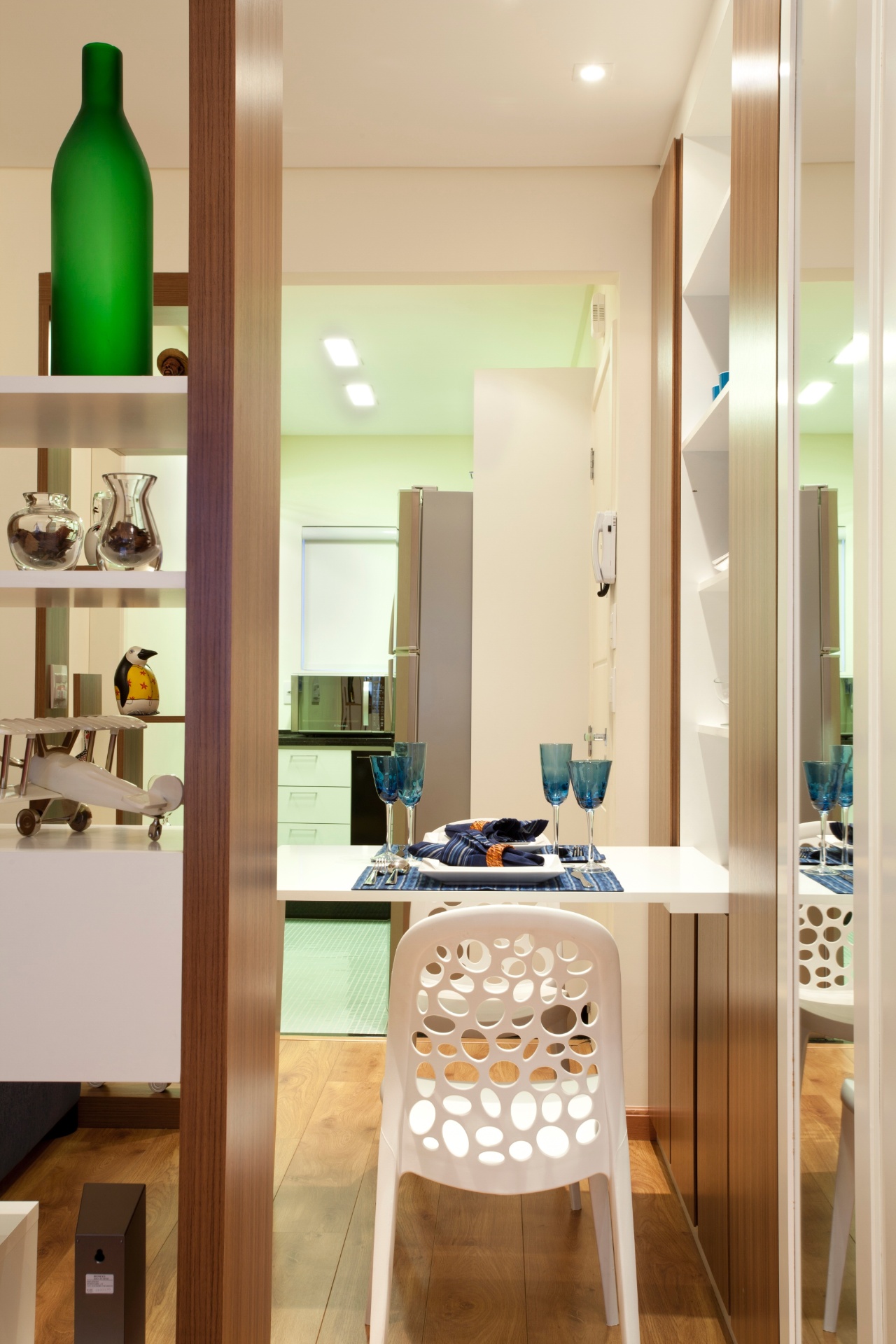 A compartimentação entre os ambientes na área seca do apartamento de 32 m² é feita pela marcenaria. A arquiteta de interiores Adriana Fontana aproveitou uma parede inteira para instalar o guarda roupas (na altura no dormitório) e o louceiro, porém, apesar de contíguos, os armários têm suas funções diferenciadas pelo revestimento das portas: laca branca e espelhos, para roupas, e amadeirado, para louças (na área de estar) - Divulgação