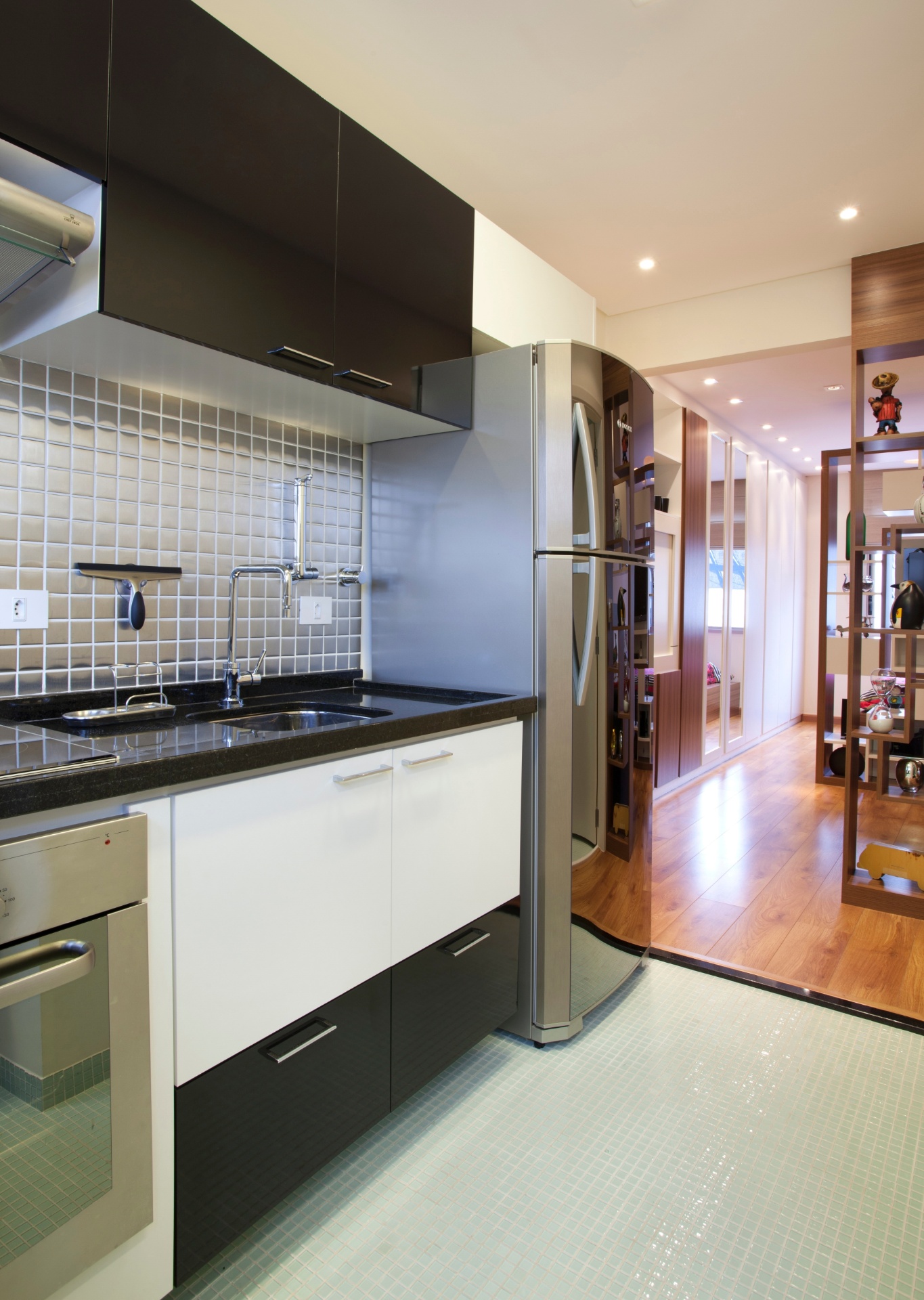 A cozinha ganhou eletrodomésticos em aço inox, que foram combinados a pastilhas com acabamento no mesmo material (Mozaik). No piso, também há pastilhas, mas elas são de vidro (Colormix). A bancada é de granito preto (Duarte Mármores e Granitos) e os móveis foram executados pela Madero Marcenaria, em MDF (Masisa) laqueado. O projeto de interiores é da designer Adriana Fontana - Divulgação