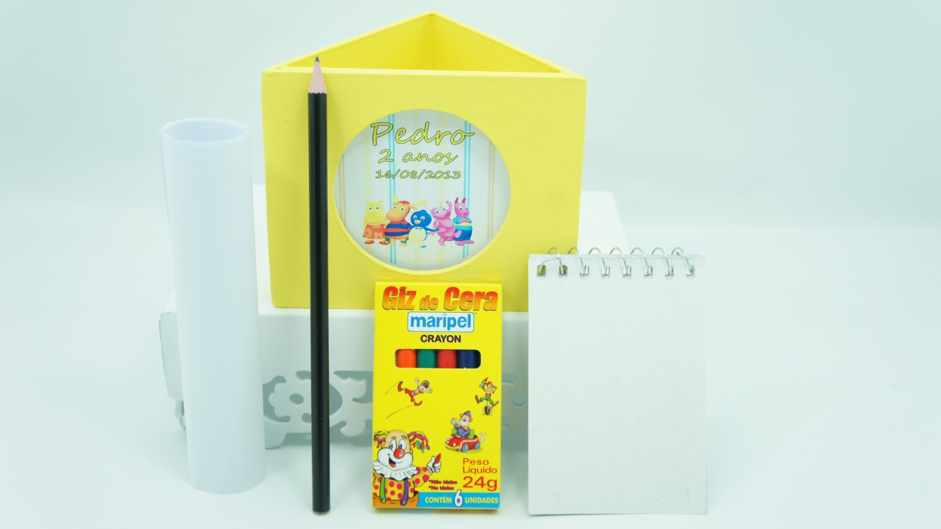 álbum com lembrancinhas úteis para festas de aniversário | Kit com porta-lápis/porta-retrato, giz de cera, lápis preto, bloco de anotações e desenhos para colorir. Da Alegria Está no Ar (www.alegriaestanoar.com.br). R$ 5,60 o conjunto (pedido mínimo de 20 unidades). Preço pesquisado em fevereiro de 2015. Sujeito a alterações - Divulgação