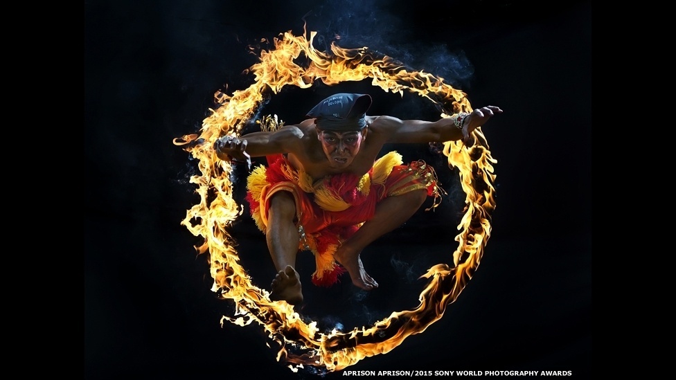 Esta imagem de Bujang Ganong saltando através de um círculo de fogo foi feita por Aprison-Aprison. Clicada na Indonésia, a foto foi selecionada para a categoria aberta Artes e Cultura - Sony World Photography Awards
