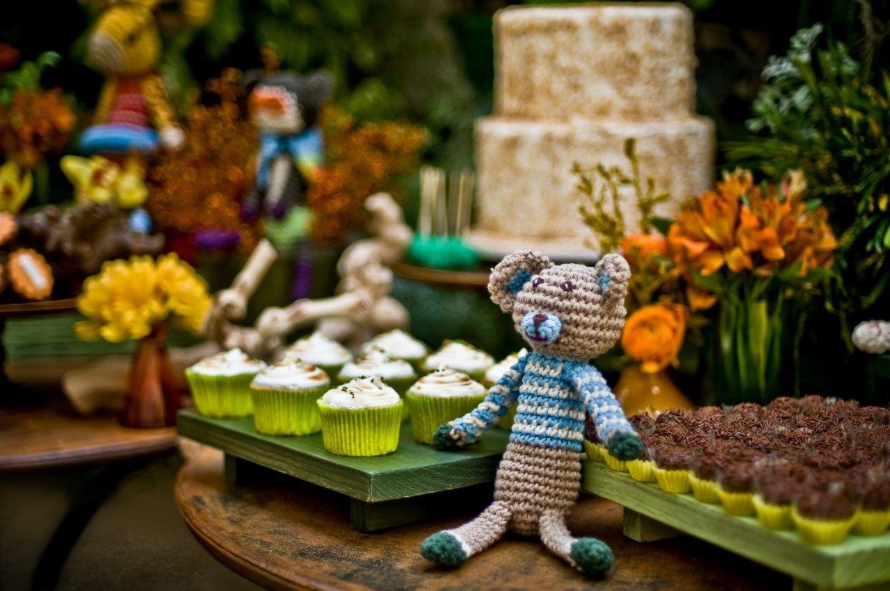 Para reforçar o tema do aniversário, uma floresta em crochê, a mesa do bolo foi montada na frente de um paredão repleto de plantas. Feito por Bruna Gauss (www.facebook.com/pages/Bruna-Gauss-Arte-em-Açúcar), o bolo era um pão-de-ló com recheio de doce de leite, abacaxi e coco. A cobertura era de marshmallow com coco queimado - Renata e Yuri Fotografia/Divulgação