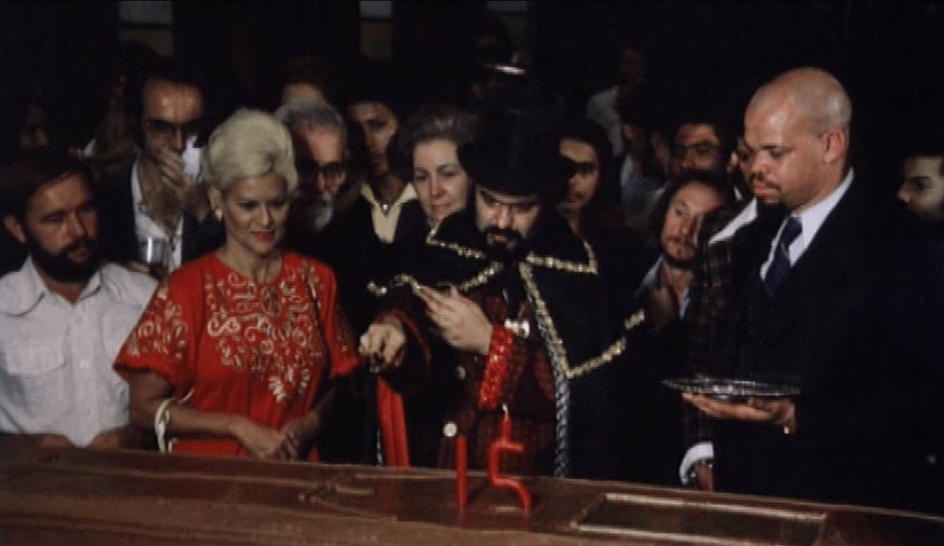 Satã trabalhava para Zé do Caixão - Mojica era constantemente acompanhado a tiracolo por Satã (à direita na imagem), seu guarda-costas e espécie de quebra galho na produção. O mulato alto e forte trabalhou também em outras produções da Boca do Lixo, sendo creditado em mais de 20 filmes. Na imagem, Mojica corta um "bolo caixão" em comemoração aos 15 anos de seu personagem - Reprodução