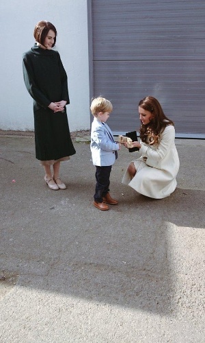 12.mar.2015 - Ator-mirim de "Downton Abbey", Oliver Barker presenteia Kate Middleton com trem de madeira para o Príncipe George. A Duquesa estava em visita ao set da série, em Londres