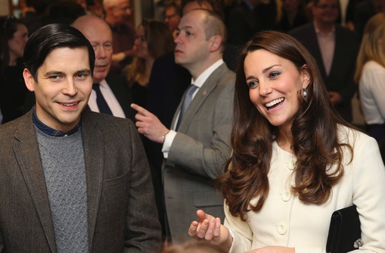 12.mar.2015 - Sorridente, Kate Middleton conversa com o ator Robert James-Collier, o Thomas de "Downton Abbey", durante visita ao set de gravações da série, em Londres