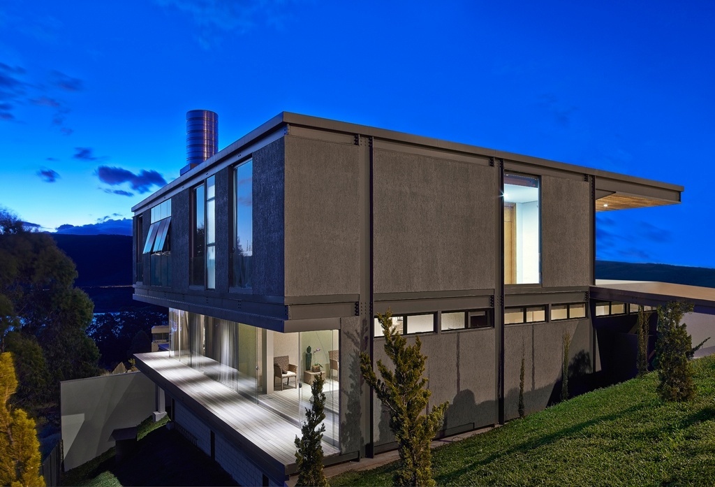 A fachada da Residência Península dos Pássaros voltada para a mata de preservação do condomínio em Nova Lima (MG) tem fechamentos predominantemente em vidro (temperado). No piso intermediário, social, os interiores estão protegidos por portas corrediças que se abrem para varanda com deck de lambris que imitam madeira (Ecoblock, feitos de PET). Para o lado da rua, as janelas são em fita (posicionadas junto à laje) para garantir a privacidade - Jomar Bragança/ Divulgação