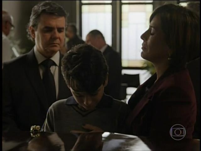 Beatriz consola o filho de Evandro durante o velório da mãe. Ela convence o empresário a jogar as cinzas da mulher no Rio Sena em Paris, na França