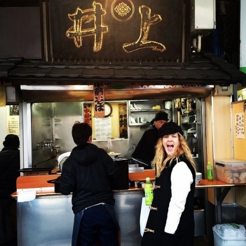 17.mar.2015 - A atriz Drew Barrymore faz careta ao posar em frente a uma barraca de comida em Tóquio, no Japão