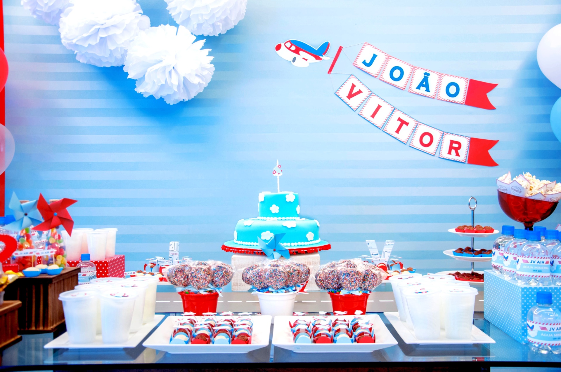 álbum com painéis para festas infantis | Um tecido azul grampeado em um painel de madeira foi usado para a decoração da festa com tema avião, feita por Liliana Loureiro (www.lilianaloureiro.com.br). Nele foram aplicados bandeirolas, impressas e recortadas, e pompons de papel de seda - Taíssa Sterim/Divulgação