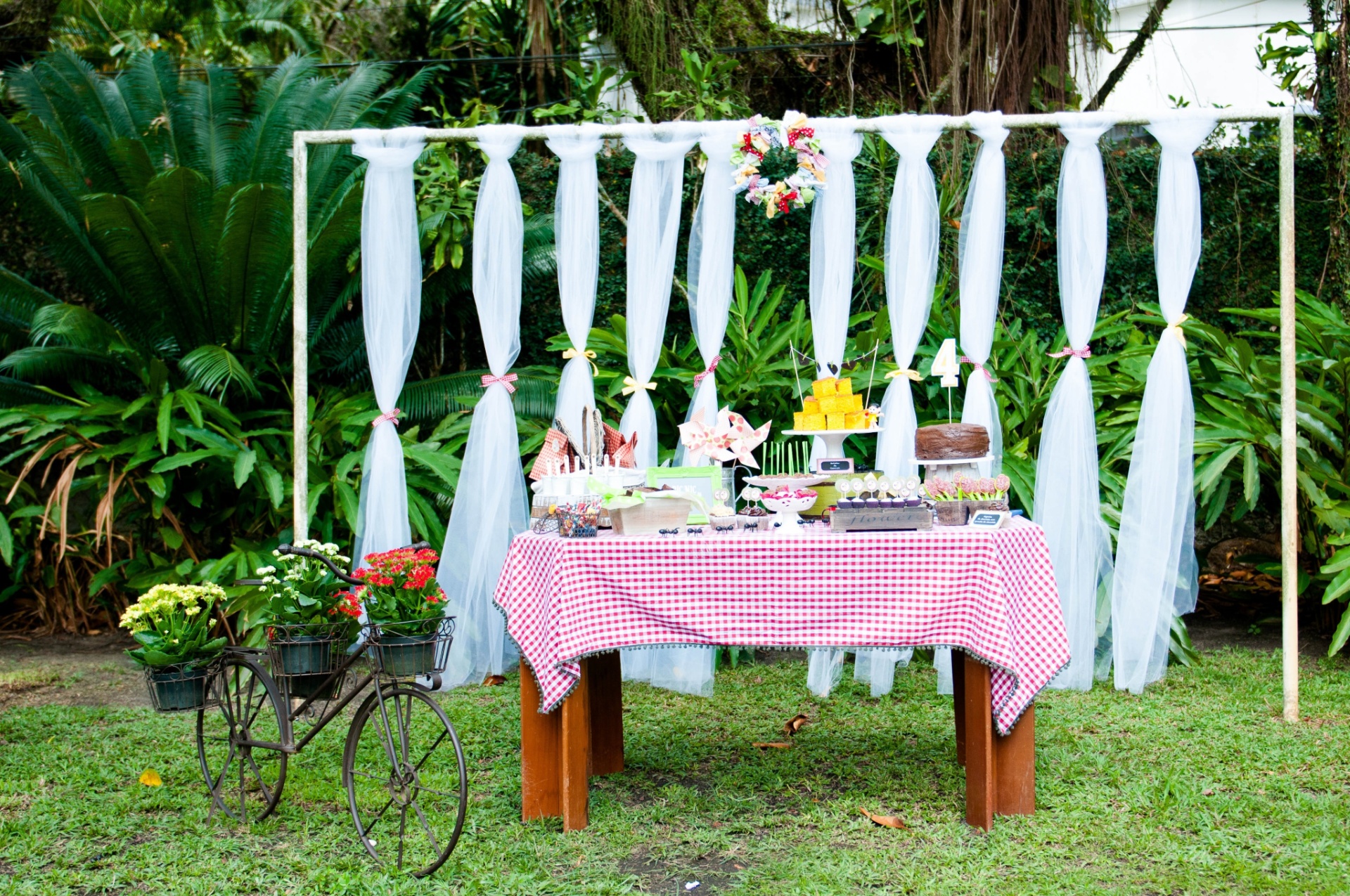 álbum com painéis para festas infantis | Realizada em um jardim, a festa com o tema piquenique da Magali, decorada por Liliana Loureiro (www.lilianaloureiro.com.br), aproveitou a estrutura de uma trave de gol para compor a decoração atrás da mesa do bolo. Nela, foram penduradas faixas de filó branco, amarradas com retalhos de tecido. No centro, uma guirlanda, também feita de retalhos de tecido, foi fixada em uma estrutura de palha - Vanessa Somellera/Divulgação