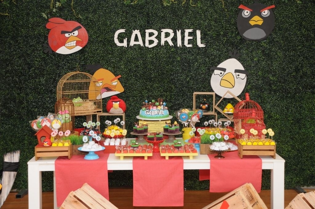 álbum com painéis para festas infantis | Na festa com tema "Angry Birds", decorada pela Jazz Assessoria em Eventos (www.jazzassessoria.com.br), um painel de metal fino, com plantas verdes artificiais, foi usado para decorar a parede atrás da mesa do bolo. Os bonecos do game e desenho e o nome do aniversariante foram feitos em peças de MDF, pintadas à mão e aplicadas com cola quente no painel - Divulgação