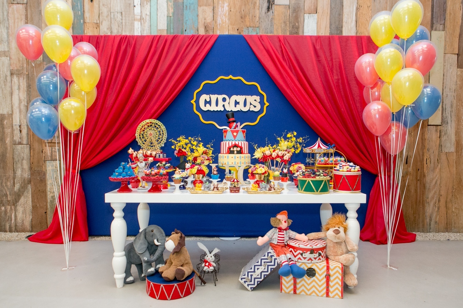 álbum com painéis para festas infantis | A festa com tema circo, da Jazz Assessoria em Eventos (www.jazzassessoria.com.br), teve um painel com estrutura metálica atrás da mesa do bolo. Coberto com tecido azul "bic", tinha, nas laterais, pano vermelho para dar acabamento de cortina. Peças em MDF, a moldura amarela e a palavra "Circus" foram costurados no centro do painel - Divulgação