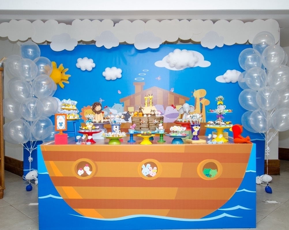 álbum com painéis para festas infantis | Na festa com tema arca de Noé, a Caixa de Poluka (www.facebook.com/pages/Caixa-de-Poluka/128795713965023) usou um painel feito de lona e aplicado em madeira para decorar a parede atrás da mesa do bolo. Para dar um efeito 3D, foram feitas nuvens e sol em feltro, que foram colados no painel - Divulgação