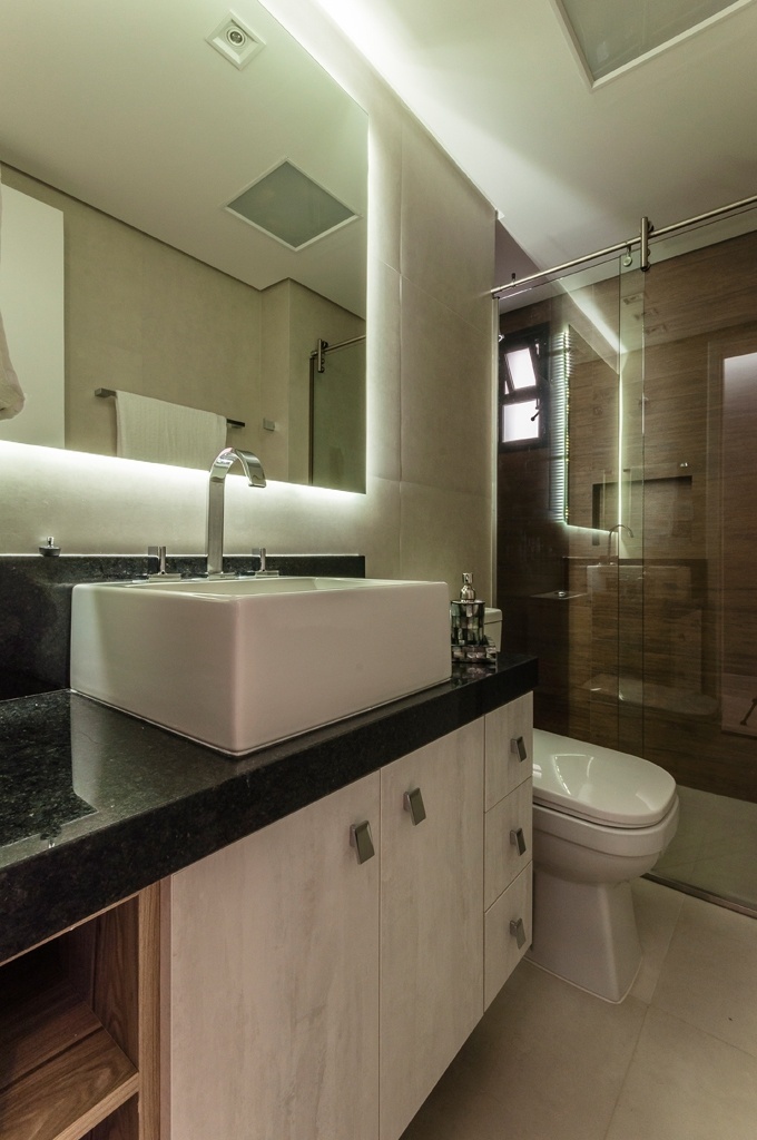 Neste banheiro com três metros quadrados e design de Ricardo Lopez, o recurso utilizado para aumentar a sensação de amplitude foi "o espelho com iluminação traseira, fixado em um chassi de alumínio", como afirma o projetista. O emprego máximo de vidro e metais polidos em lugar de estruturas de alumínio também criam a ilusão de maior espaço, efetivamente racionalizado pela marcenaria sob a bancada - Henrique Ribeiro/ Divulgação