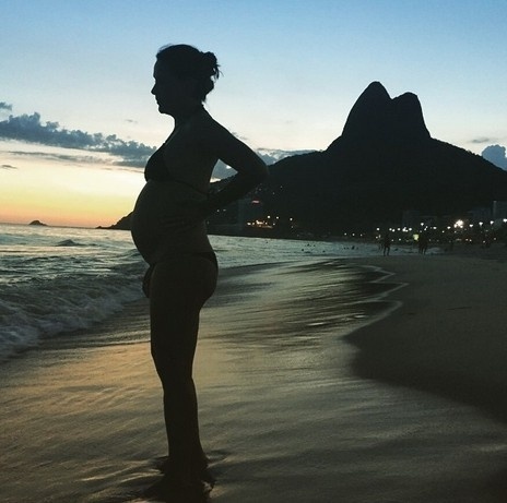 6.abr.2015 - Na reta final da gravidez, Carolina Ferraz exibe a silhueta com o barrigão na praia durante o pôr do sol